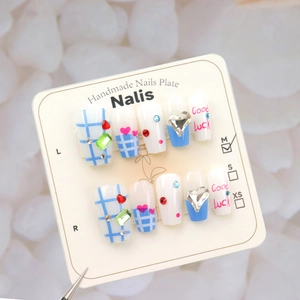 Detailed view of handmade blue checkered press-on nails with 3D gems and heart motifs