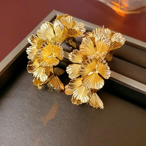 Macro view of gold petal earrings with layered metallic texture on a jewelry tray