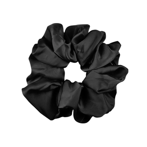 Detail of a black elastic satin scrunchie showing glossy fabric texture and pleats