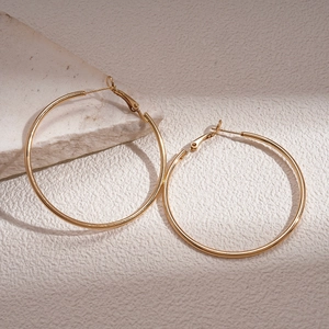 Close-up of glossy gold hoop earrings on a textured stone base with minimalist lighting