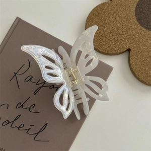 Dettaglio della molletta per capelli a farfalla bianco perlato su un libro con luce naturale