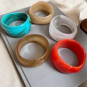 Detailed view of five chunky irregular resin bangles in amber, green, and red colors