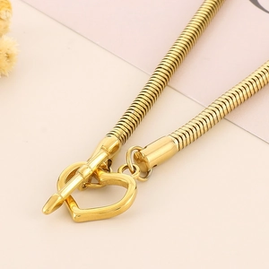 Detail of gold snake chain necklace featuring a heart-shaped OT toggle clasp and high polish