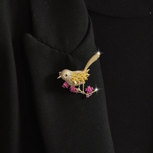 Exquisite gold bird brooch with white zircon on black suit lapel with pink flowers
