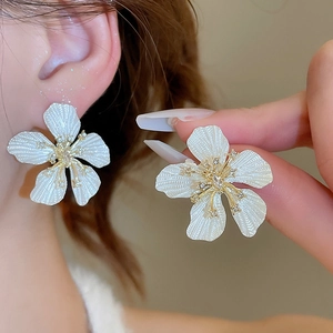 Macro shot of white petal flower stud earrings with textured finish and zircon centers