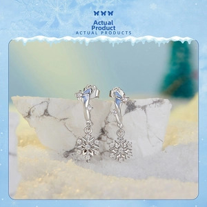 Close-up of snowflake earrings with blue enamel and cubic zirconia on snow background