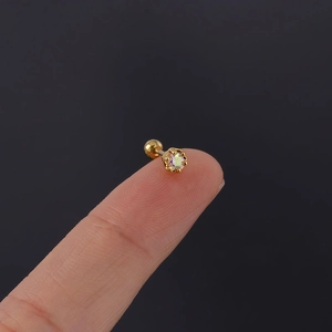 Macro view of a 20G gold stainless steel cartilage stud with rainbow zircon on fingertip