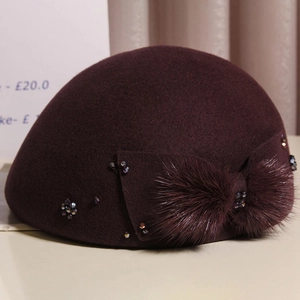 Close-up of wine red wool beret featuring a fur bow and hand-stitched crystal beads