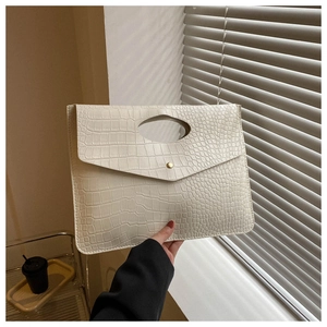 Detail of cream white tote with crocodile texture and unique cut-out handle design