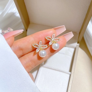 Macro view of gold floral stud earrings with sparkling crystals and white pearls