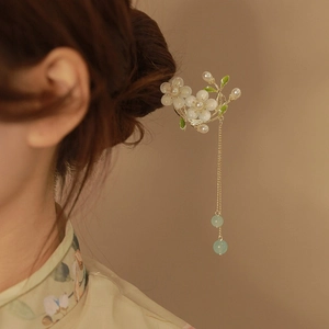 Détail d'une épingle à cheveux muguet avec perles blanches et pompons en chaîne dorée