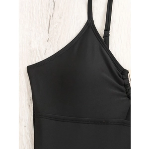 Detail of black V-neck swimsuit with adjustable straps and ruched sides on wood