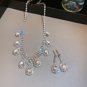 Close-up of sparkling silver necklace and teardrop crystal earrings on a display tray