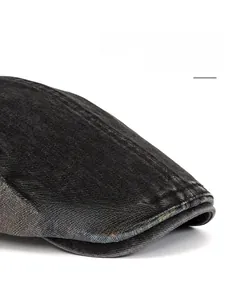 Detail of washed black denim fabric with visible twill texture on a newsboy flat cap