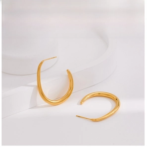 Détails de grandes boucles d'oreilles dorées en U sur blocs de pierre blancs