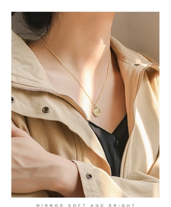 Close-up of model wearing gold star stamp pendant necklace with retro minimalist design