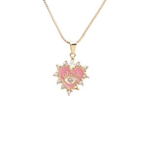 Collier cœur doré avec œil protecteur rose et pointes en zircone sur fond blanc épuré