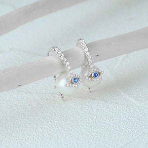 Detail of S925 silver devil eye pearl earrings with blue zircon and pavé stones