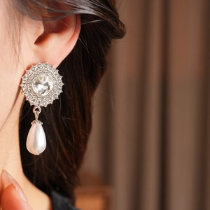 Close-up of a model wearing luxury silver-tone earrings with pearls and crystals