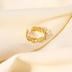 Detailed close-up of golden peace sign open ring on soft beige silk background