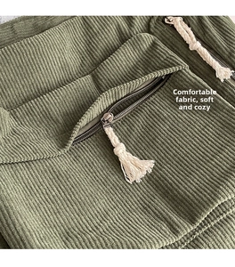 Détail du sac bandoulière en velours côtelé vert avec fermeture éclair et gland en coton