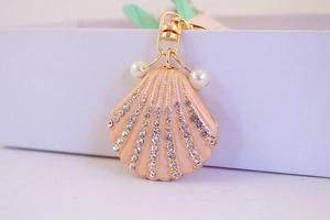 Macro detail of pink shell keychain with gold plating, sparkling rhinestones and pearls