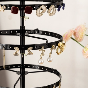 Rotating black metal multi-tier jewelry rack displaying various elegant earrings
