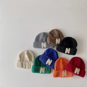 Colorful knitted winter beanies for kids featuring letter N patch and ear protection