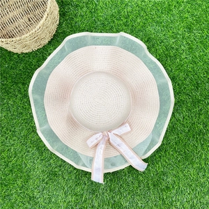 Vue de dessus d'un chapeau de paille beige avec bord en dentelle et ruban sur herbe
