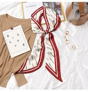 Detail of elegant wine red and beige silk twilly scarf with script lettering and stripes