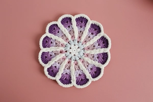 Macro shot of handmade crochet coaster with floral gradient pattern and textured yarn
