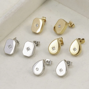Detailed close-up of gold and silver rectangle and teardrop star stud earrings on a velvet tray