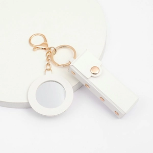 White faux leather lipstick pouch with gold hardware, mirror charm, and snap closure