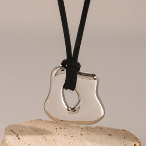 Irregular liquid metal silver pendant on black cord necklace over a natural stone