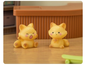 Macro shot of cute yellow resin foxes in yawning and sitting poses for desk decor
