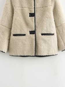 Detail of beige faux fur coat with black faux leather trim and round button closures