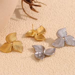 Macro detail of three-petal leaf earrings in gold and silver finish with linear texture