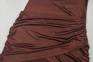 Detail of ruched design on sleek brown bodycon dress with gathered fabric texture