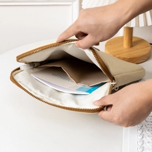 Close-up of beige cat embroidery laptop sleeve interior with pockets and office supplies