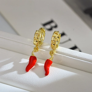Detailed macro view of gold-plated hoop earrings with vibrant red chili pepper pendants
