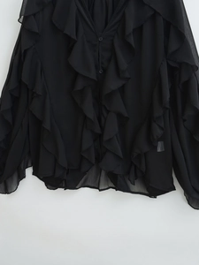 Detail of black chiffon shirt featuring tiered ruffles and delicate button accents