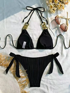 Detail of black pleated bikini with gold chain accents and textured fabric surface