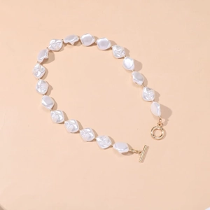 Baroque irregular pearl necklace with gold OT clasp on a warm apricot background