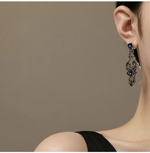 Close-up of vintage silver earrings with blue gemstones and hanging droplet tassels