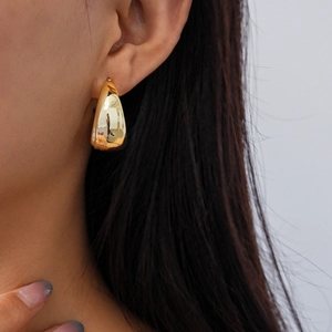 Close-up of elegant gold teardrop earring worn by a model showcasing metallic shine