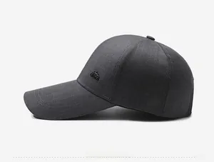 Detail of dark gray baseball cap showing textured fabric and metal logo ornament