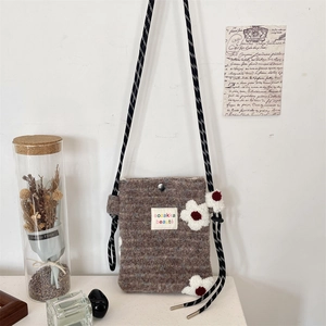 Detailed texture of brown plush shoulder bag with three red and white crochet flowers