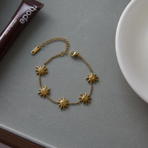 Dettaglio di un bracciale a sole in acciaio dorato 18K con catenella di estensione regolabile