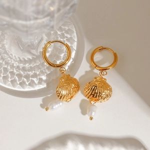 Detail of golden shell earrings with white baroque pearls on a minimalist background