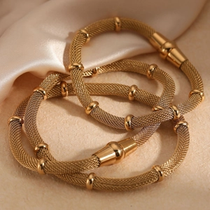 Elegant gold mesh chain bracelets with cylindrical clasps on silk fabric background